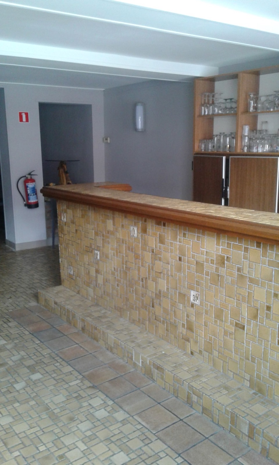 Comptoir bar en mosaïque ocre du café du Salon de Graty avec étagères à verres