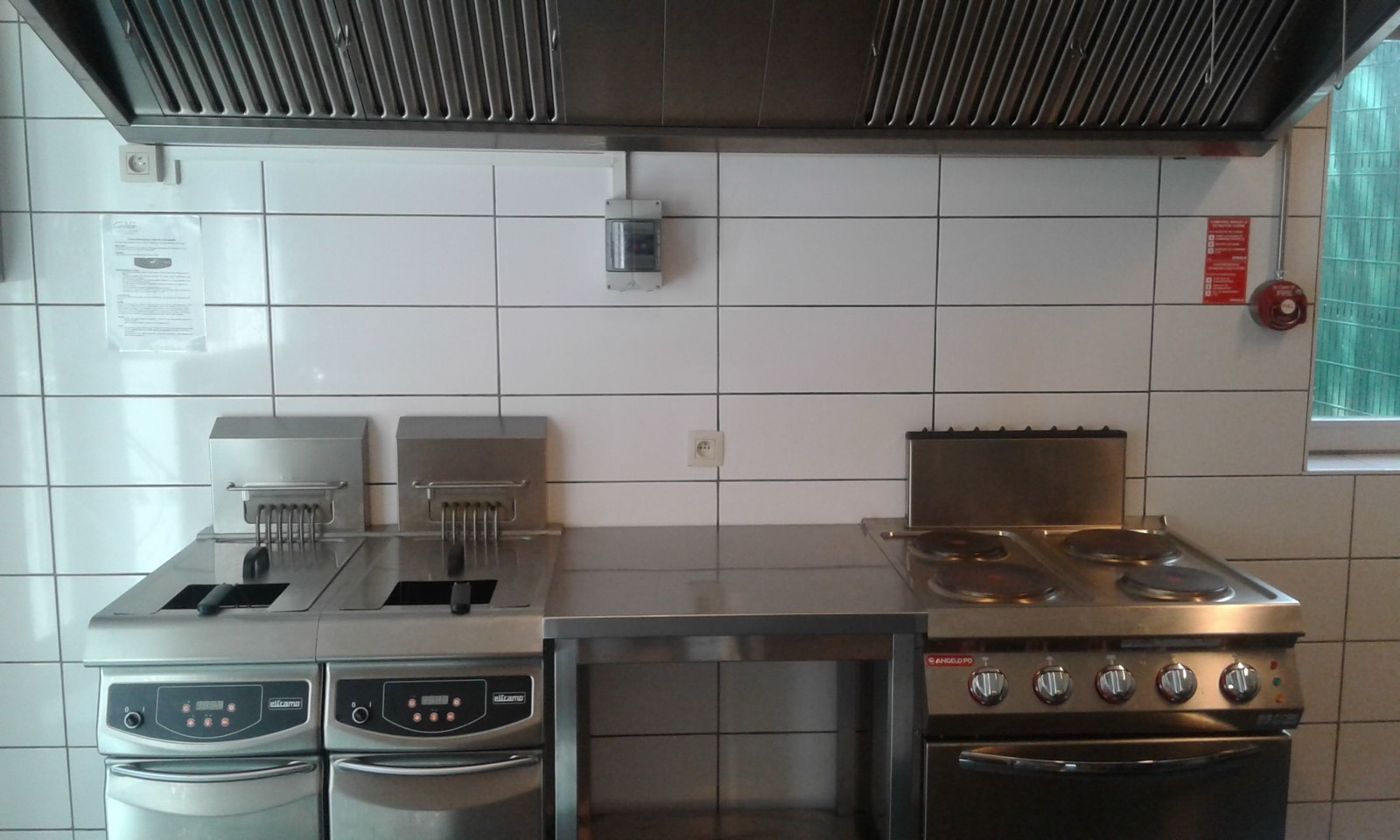 Piano de cuisson à gaz et friteuses en inox sous hotte dans la cuisine professionnelle