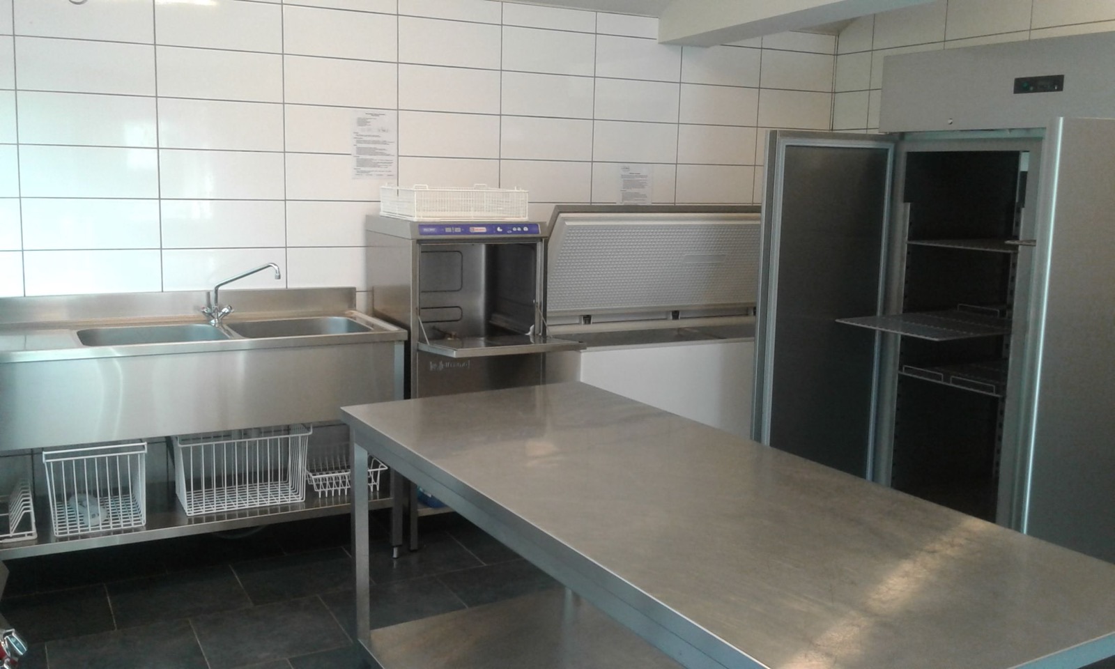 Zone de plonge de la cuisine : lave-vaisselle, éviers inox et armoire frigorifique