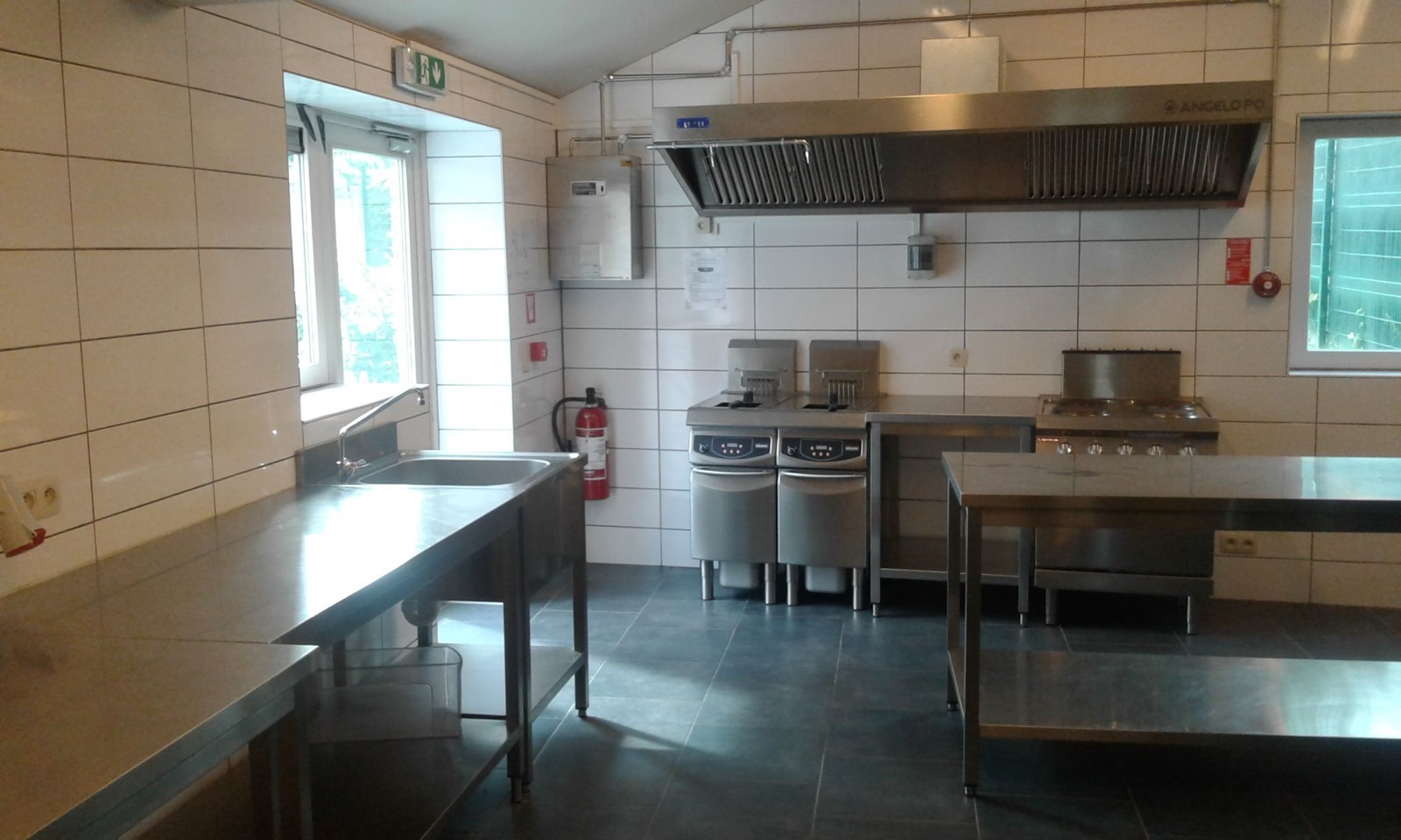Cuisine professionnelle de la grande salle : plans de travail en inox, friteuses et piano de cuisson