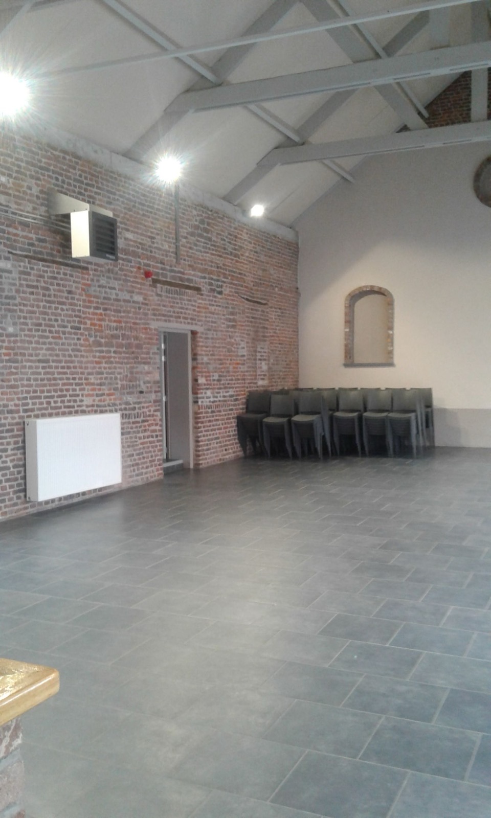 Intérieur de la grande salle du Salon de Graty : vaste espace aux murs en briques apparentes et charpente métallique