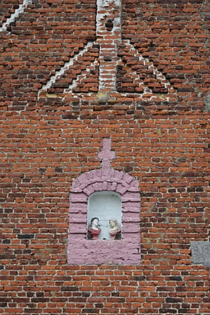 Petite niche encadrée de rose abritant deux statuettes, dans un pignon en briques