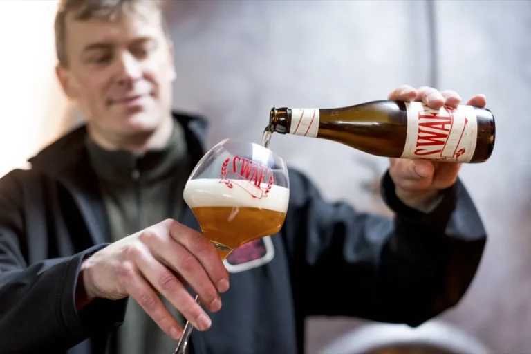 Un brasseur verse une bière ambrée dans un verre à pied