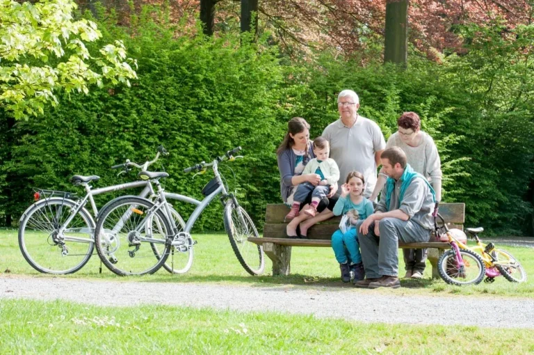 Famille assise sur un banc dans un parc, les vélos garés à côté