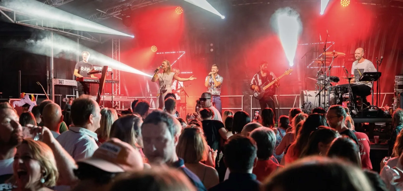 Groupe de musique sur scène avec éclairages rouges devant un public nombreux lors d'un concert à Silly