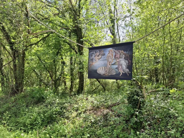 Reproduction de La Naissance de Vénus de Botticelli suspendue à une corde dans un sous-bois