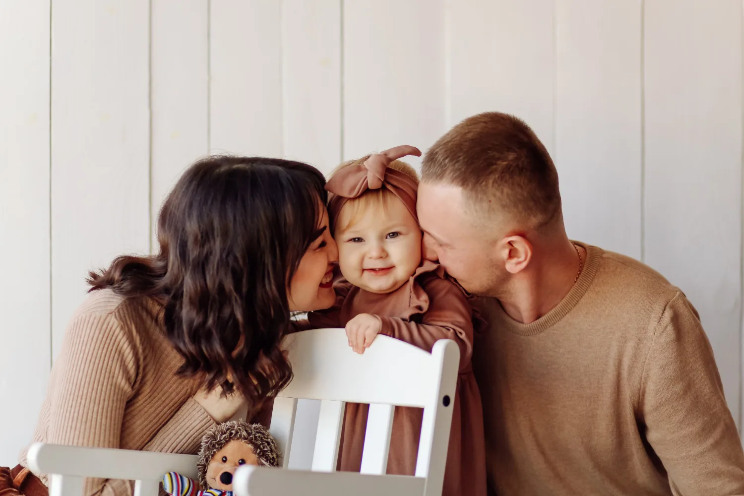 Des parents complices entourant et embrassant leur bébé souriant