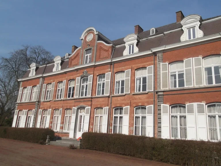 Longue façade en briques d'un château aux volets blancs