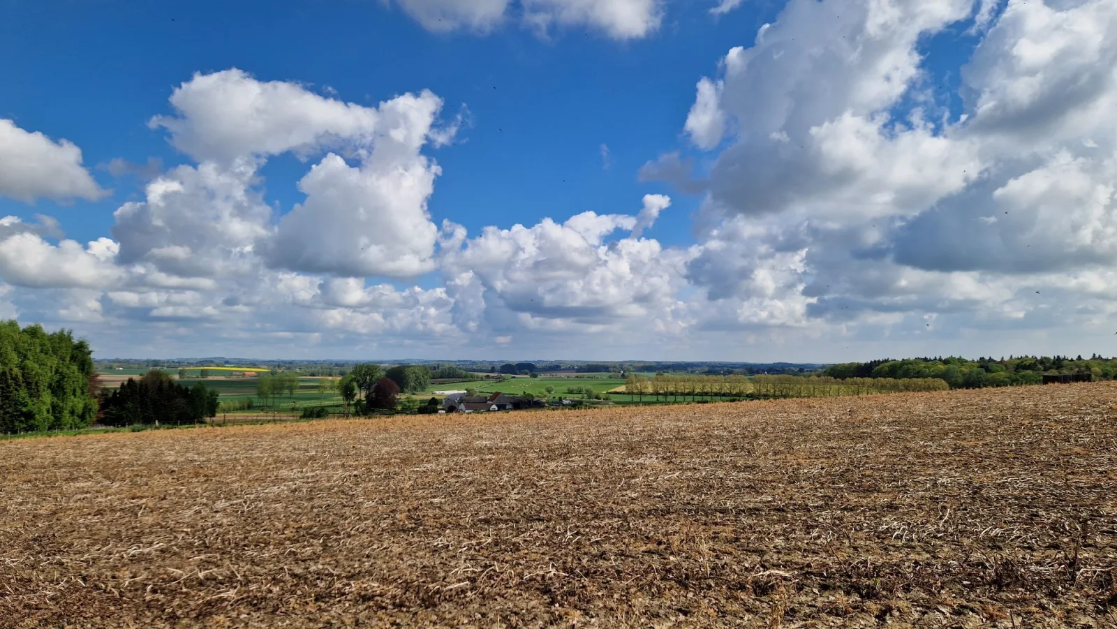 Panorama sur les champs cultivés et les collines vallonnées de la campagne de Silly sous un ciel nuageux
