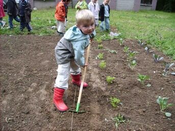 Enfant jardinant dans le potager d'une école dans le cadre des projets Slow Food