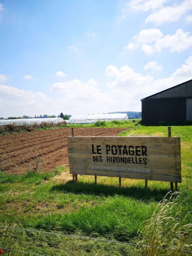 Panneau « Le potager des Hirondelles » au bord d'un champ cultivé