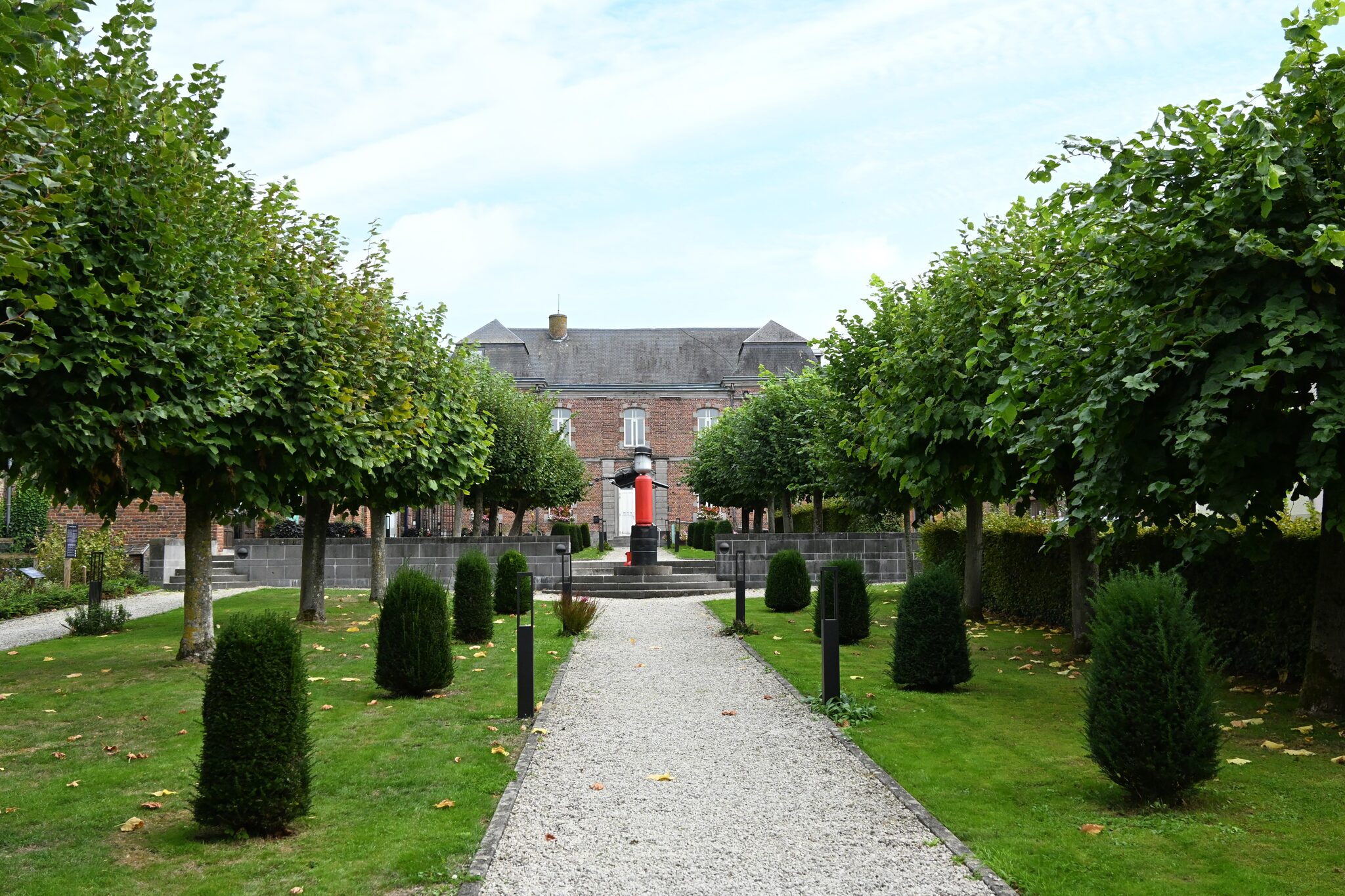 Allée du parc communal de Silly bordée d’arbres taillés et d’ifs, menant à la Maison communale