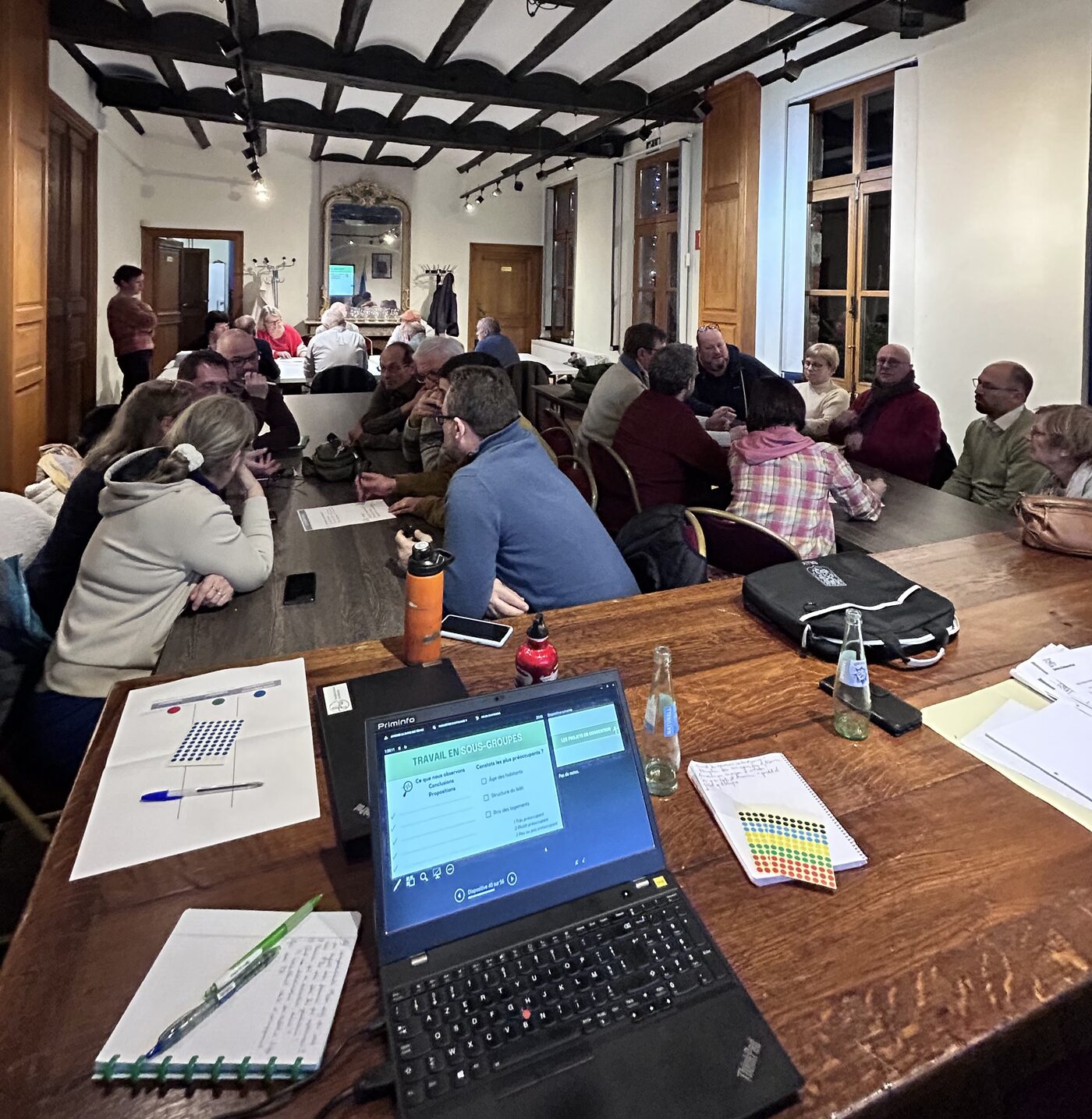 Une réunion de la CLDR en sous-groupes, autour de tables dans une salle aux poutres apparentes ; au premier plan, un ordinateur portable affiche « Travail en sous-groupes ».